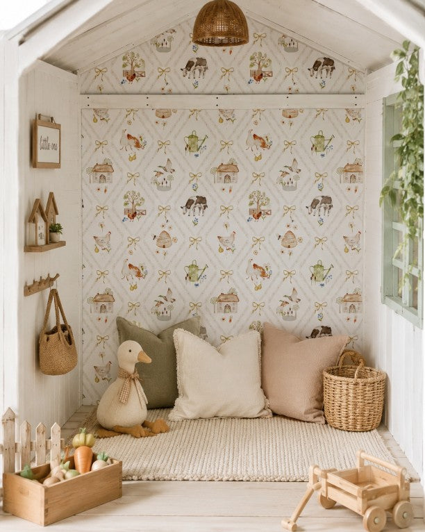 Beautifully styled children’s cubby featuring whimsical farm-themed wallpaper with cows, chickens, cottages, bows and garden details, paired with soft neutral cushions, natural timber toys and woven accessories.