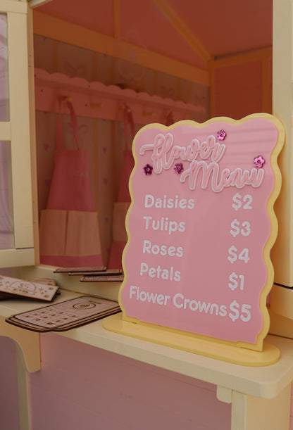 Pink menu board with prices in a dollhouse setting