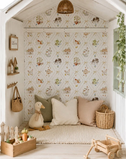 Beautifully styled children’s cubby featuring whimsical farm-themed wallpaper with cows, chickens, cottages, bows and garden details, paired with soft neutral cushions, natural timber toys and woven accessories.