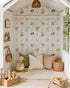 Beautifully styled children’s cubby featuring whimsical farm-themed wallpaper with cows, chickens, cottages, bows and garden details, paired with soft neutral cushions, natural timber toys and woven accessories.